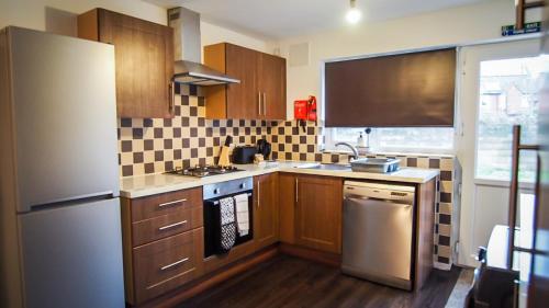 a kitchen with wooden cabinets and a white refrigerator at Ur City Pad - 4 bedrooms - 4 bathrooms - Somerset House in Birmingham