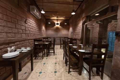 um restaurante com mesas e cadeiras de madeira e uma parede de tijolos em Baijoo Niwas em Jodhpur