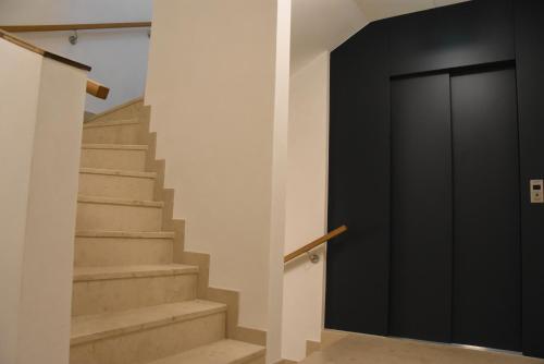 a hallway with stairs and a black door at meerZEIT Norderney in Norderney