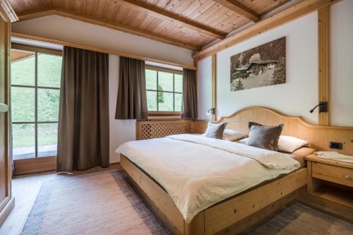 a bedroom with a large bed and windows at Arbea Apartments in Ortisei