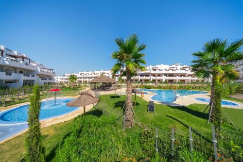 a resort with a swimming pool and palm trees at Apartment Cerezas in San Juan de los Terreros