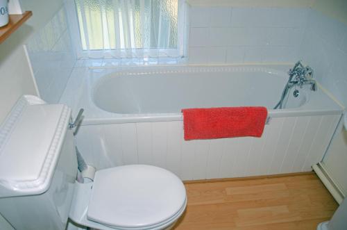 a white bathroom with a toilet and a bath tub at 1 Hope Cottage in Spilsby