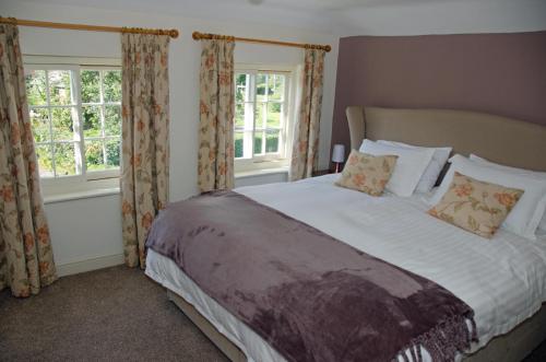 a bedroom with a large bed and two windows at 1 Hope Cottage in Spilsby