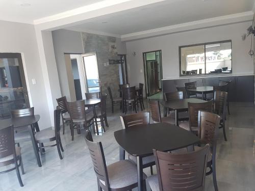 a dining room with tables and chairs and windows at Sunflower Guesthouse in Vanderbijlpark