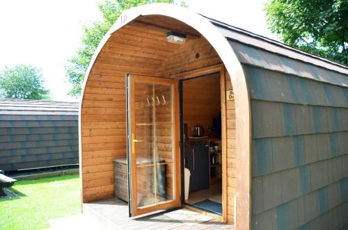 an arched entrance to a wooden shed with a door at Woodclose Park in Kirkby Lonsdale