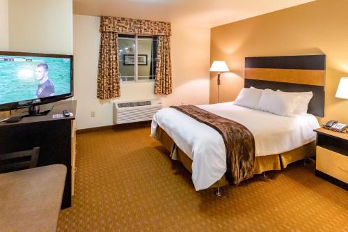 a hotel room with a bed and a flat screen tv at Welcome Suites - Minot, ND in Minot