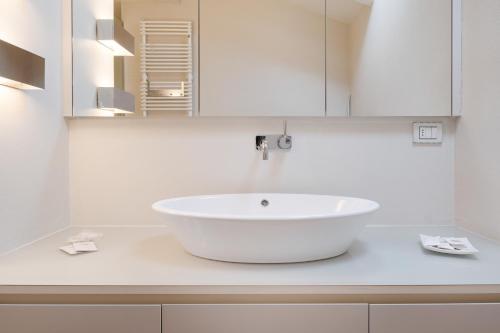 W białej łazience znajduje się umywalka i lustro. w obiekcie In the Shadow of the Two Towers w Bolonii