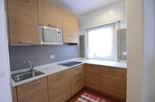 a kitchen with wooden cabinets and a sink and a window at Continental 102 - 4 beds in San Vito di Cadore