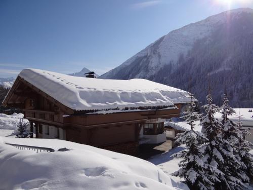 a building covered in snow with a mountain in the background at Landhaus Erlzette in Tux