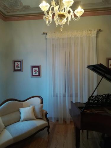 a living room with a white couch and a piano at Villa delle Rose - Hotel Paradiso in Amandola