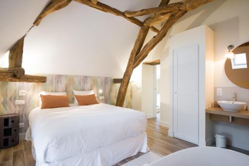 ein Schlafzimmer mit einem weißen Bett und einem Waschbecken in der Unterkunft La Maison Deveney Mars in Puligny-Montrachet