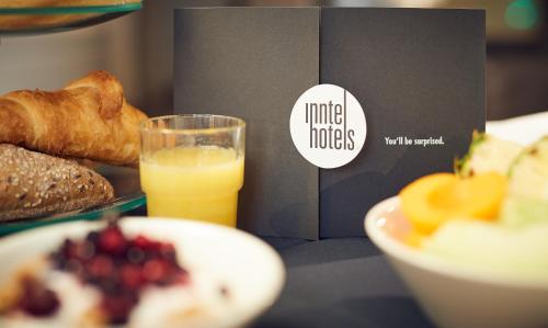 a table with a plate of food and a glass of orange juice at Inntel Hotels Amsterdam Centre in Amsterdam