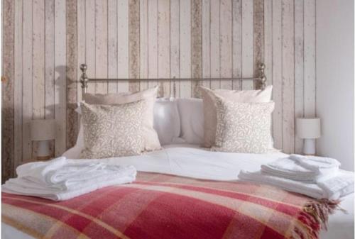 Una cama con sábanas blancas y almohadas. en Corner Cottage Mevagissey en Mevagissey