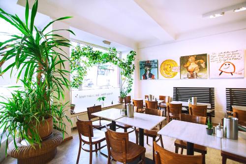 a restaurant with tables and chairs and plants at Pension Peters – Das andere Hotel in Berlin