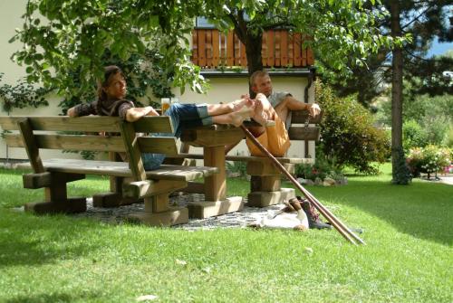 two men sitting on a park bench in the grass at Landhaus & Appartementhaus Haussteiner in Dorfgastein