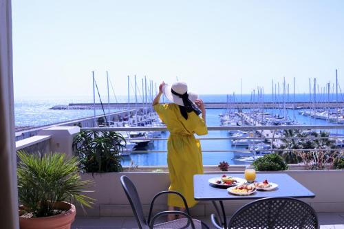 a woman in a yellow dress standing on a balcony at Aregai Marina Hotel & Residence in Santo Stefano al Mare