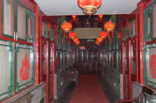 a hallway with red walls and chairs and lights at Qianmen Courtyard Hotel in Beijing