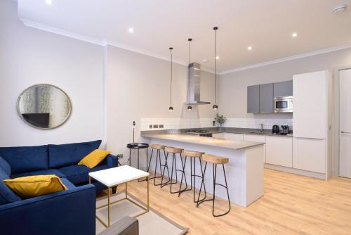 a kitchen and living room with a blue couch at Destiny Scotland Charlotte Square Apartments in Edinburgh