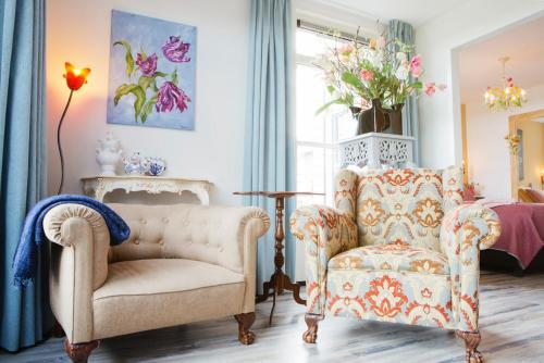 un soggiorno con divano, sedia e finestra di Maison la Tulipe a Zoutelande