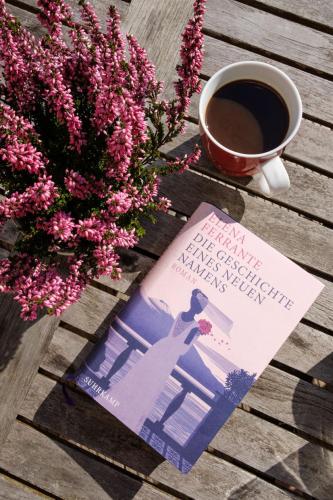 a book and a cup of coffee on a table with flowers at Fewo-Mundi in Egestorf