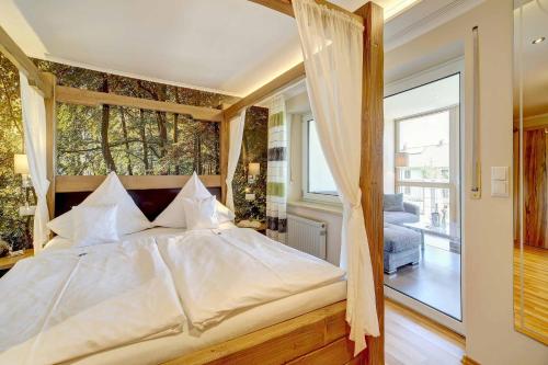 a bedroom with a bed with a large window at Hotel Hirschenstein in Achslach