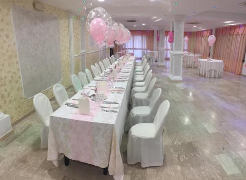 una fila de mesas con sillas blancas y globos rosas en B&B Belvedere, en Zungri