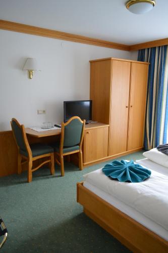 a hotel room with a bed and a desk and a table at Frühstückspension Christina in Tux