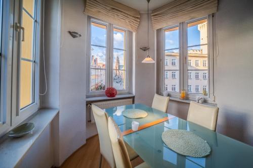 comedor con mesa de cristal, sillas y ventanas en Luxury Vision Apartment, en Opole