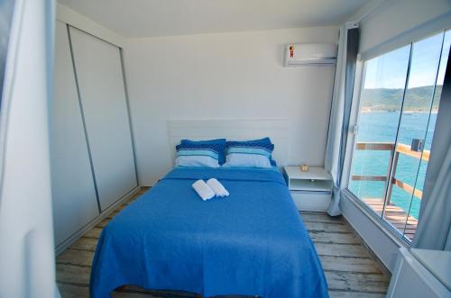 a bedroom with a blue bed with two towels on it at Casa Santorini RJ in Arraial do Cabo
