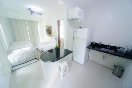 a small white kitchen with a refrigerator and a table at Pousada Toca dos Aventureiros in Barreirinhas