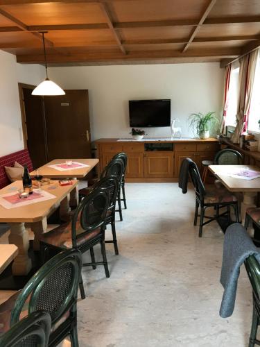 a restaurant with tables and chairs and a flat screen tv at Frühstückspension Christina in Tux