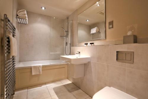 a bathroom with a sink and a tub and a toilet at Belmont Hotel Leicester in Leicester