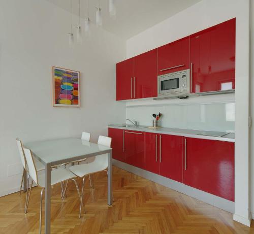 ミラノにあるミラン アパートメント レンタルのキッチン(赤いキャビネット、テーブル、椅子付)