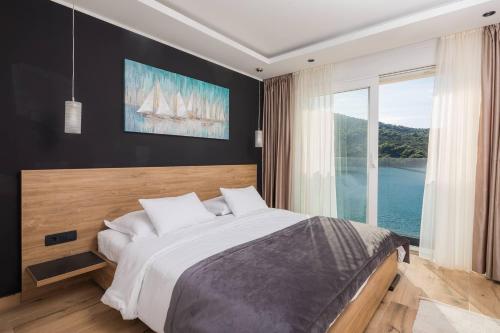 een slaapkamer met een groot bed en een groot raam bij Beachfront Luxury Villa in Vinišće