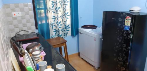 una pequeña cocina con nevera negra en una habitación en DG House, en Patnem