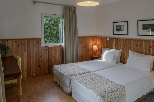 Furnas Lake Forest Living في فورناس: غرفة نوم بسرير ابيض ومكتب ونافذة