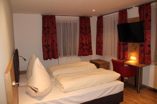 Schlafzimmer mit einem Bett, einem TV und roten Vorhängen in der Unterkunft Gasthof Zur Post in Schwabhausen bei Dachau