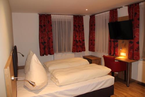 a bedroom with a bed and a television and red curtains at Gasthof Zur Post in Schwabhausen bei Dachau