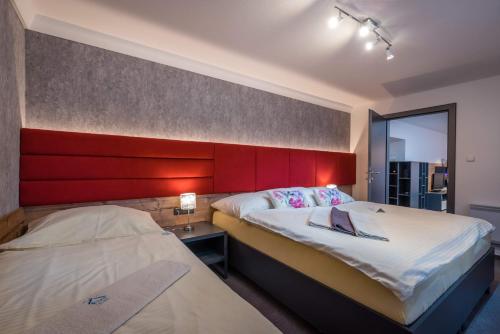 een slaapkamer met 2 bedden en een rood hoofdeinde bij Apartman Smokovec in Nový Smokovec