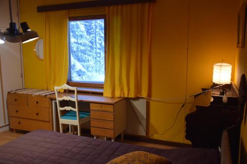 1 dormitorio con cama, escritorio y ventana en Old wooden house 20 min from Koli, en Tuopanjoki