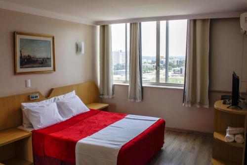 a hotel room with a bed and a large window at Airam Brasília Hotel in Brasilia