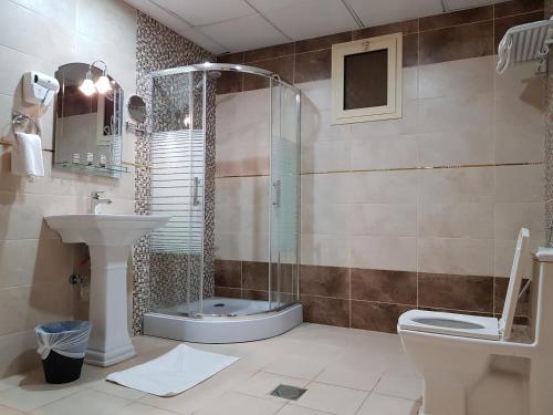 uma casa de banho com um chuveiro, um WC e um lavatório. em Farha International 2 Residential Units em Jidá