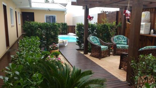 un patio con piscina, sillas y plantas en Pousada Bela Pinheira, en Palhoça