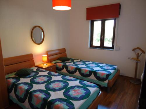 a bedroom with two beds and a mirror and a window at Casa da LAGOA (Sesimbra) in Lagoa de Albufeira