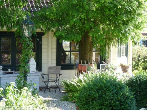a house with a tree and a bench in the yard at COSY & NATURAL *FIREPLACE*GARDEN*2 BIKES in Heinenoord