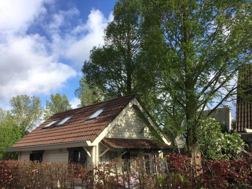a house with a brown roof and a tree at COSY & NATURAL *FIREPLACE*GARDEN*2 BIKES in Heinenoord