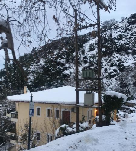 a house covered in snow in front of a mountain at Archontiko tou Ziaka in Ipáti