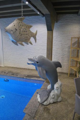 a statue of a dolphin next to a swimming pool at De Blockhut in Grône