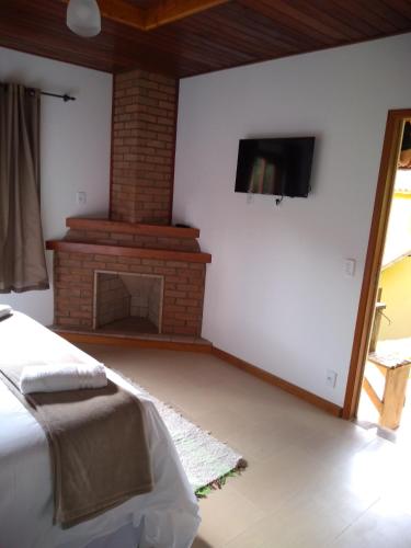 a living room with a fireplace and a bed at Pousada Sitio do Visconde in Visconde De Maua