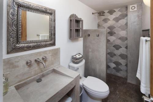 een badkamer met een wastafel, een toilet en een spiegel bij Villa Robalo A in Sayulita